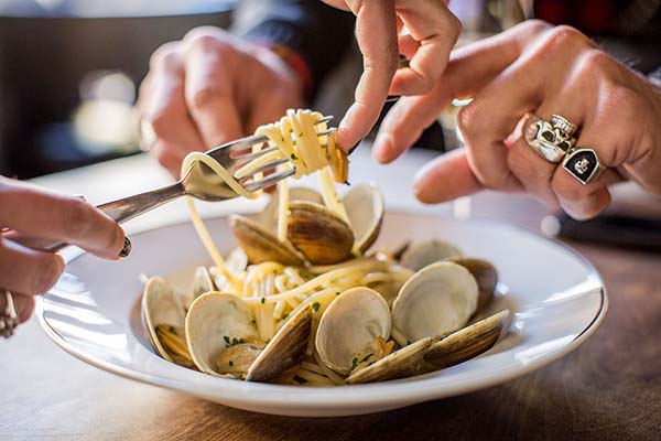 Hands food styling pasta on a fork at an Italian restaurant.
